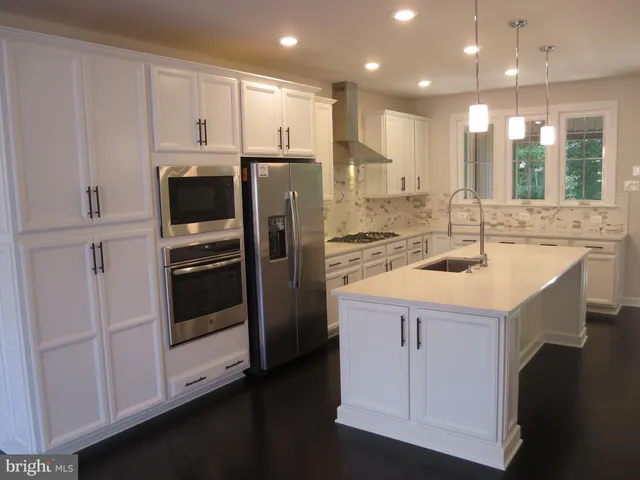 a kitchen with kitchen island white cabinets and refrigerator