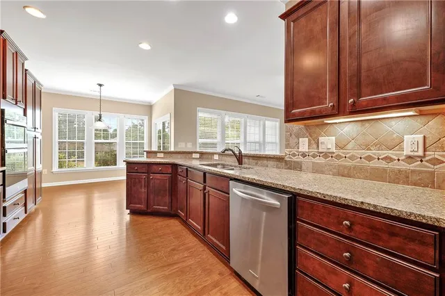 a kitchen with stainless steel appliances granite countertop wooden cabinets a sink and dishwasher with wooden floor