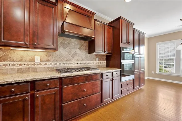 a kitchen with stainless steel appliances granite countertop wooden cabinets a stove top oven a sink and dishwasher