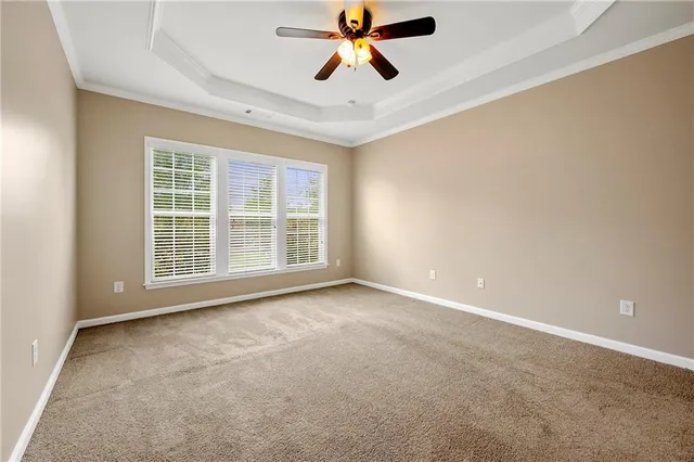 a view of an empty room with window and a ceiling fan