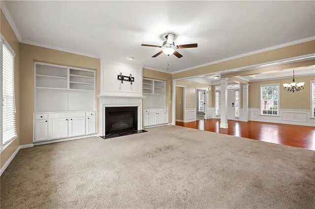 a view of an empty room with chandelier fan and fire place