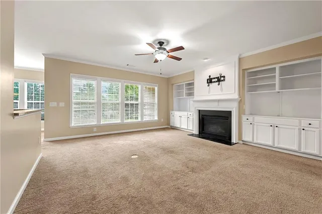an empty room with windows and fireplace