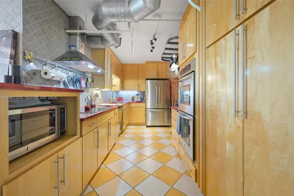 a view of a kitchen with stainless steel appliances granite countertop a refrigerator and a stove top oven