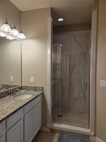 a bathroom with a granite countertop sink a mirror and a shower
