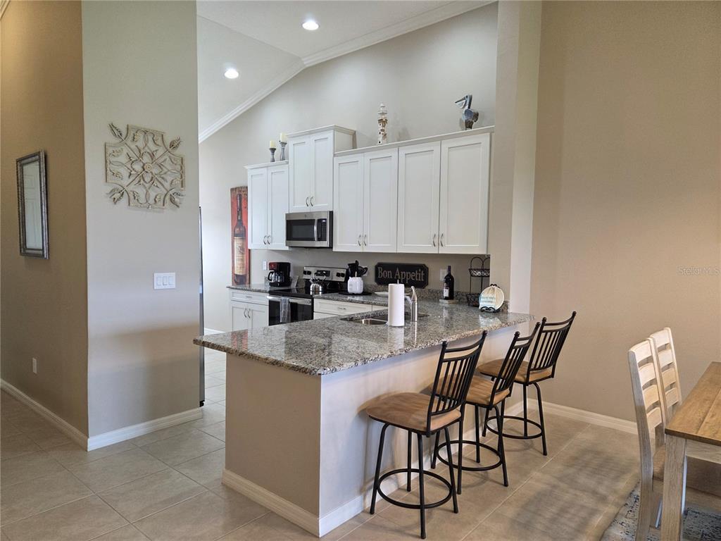 13703 Messina Loop, Unit 202 Bradenton, FL 34211 - Photo 8 of 42 a kitchen with stainless steel appliances granite countertop a stove top oven a sink a refrigerator with white cabinets and wooden floor