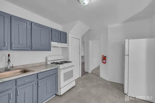 a kitchen with cabinets a sink and white appliances