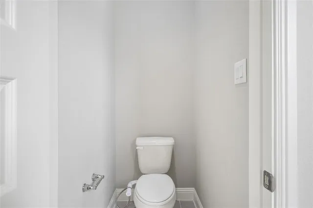 a white toilet sitting next to a white wall