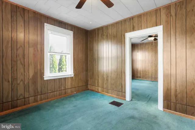 a view of a refrigerator in kitchen and an empty room