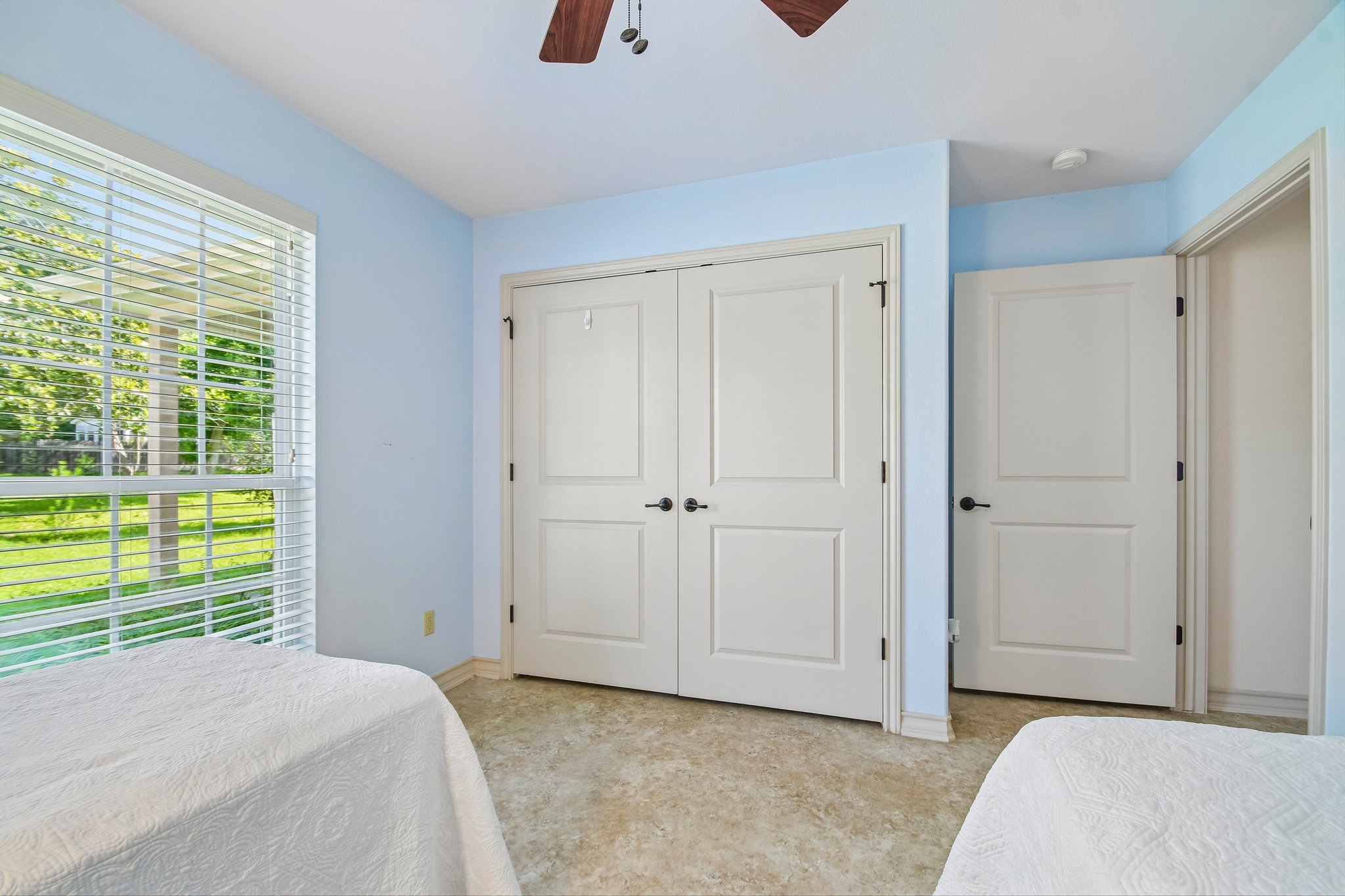 307 West 4th Street Elgin, TX 78621 - Photo 27 of 40 Room featuring light blue wall paint, a large window with white blinds, neutral-toned flooring, and white paneled doors with dark hardware