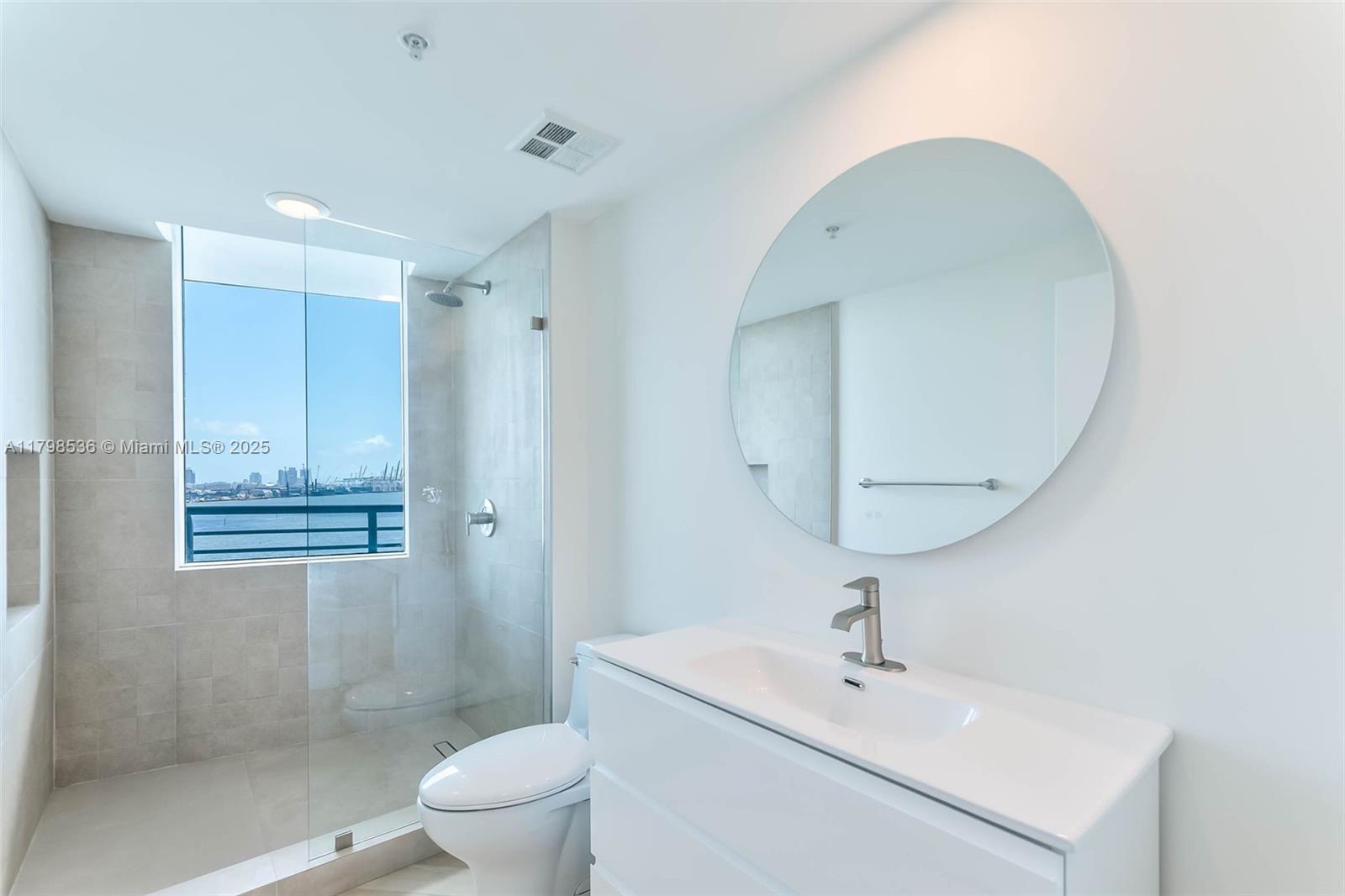 335 South Biscayne Boulevard, Unit 1012 Miami, FL 33131 - Photo 3 of 14 a bathroom with a sink a toilet and a mirror