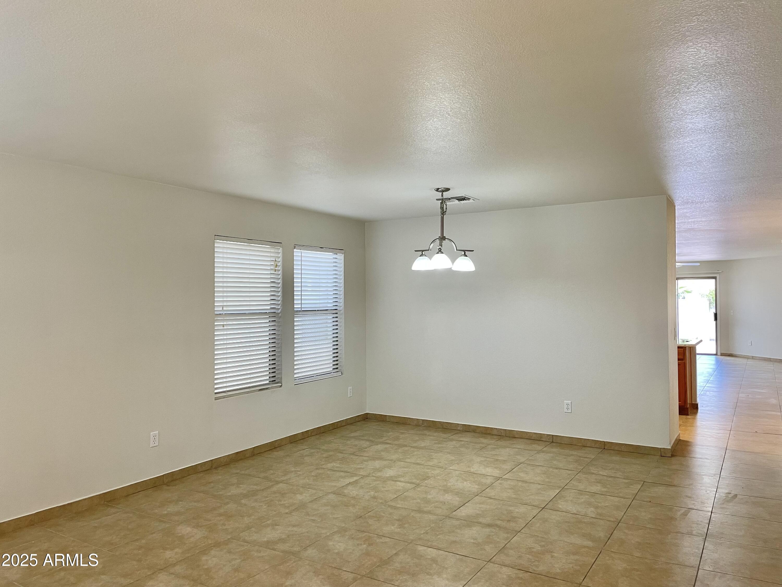 1002 East Arabian Drive Gilbert, AZ 85296 - Photo 3 of 23 an empty room with chandelier fan and windows