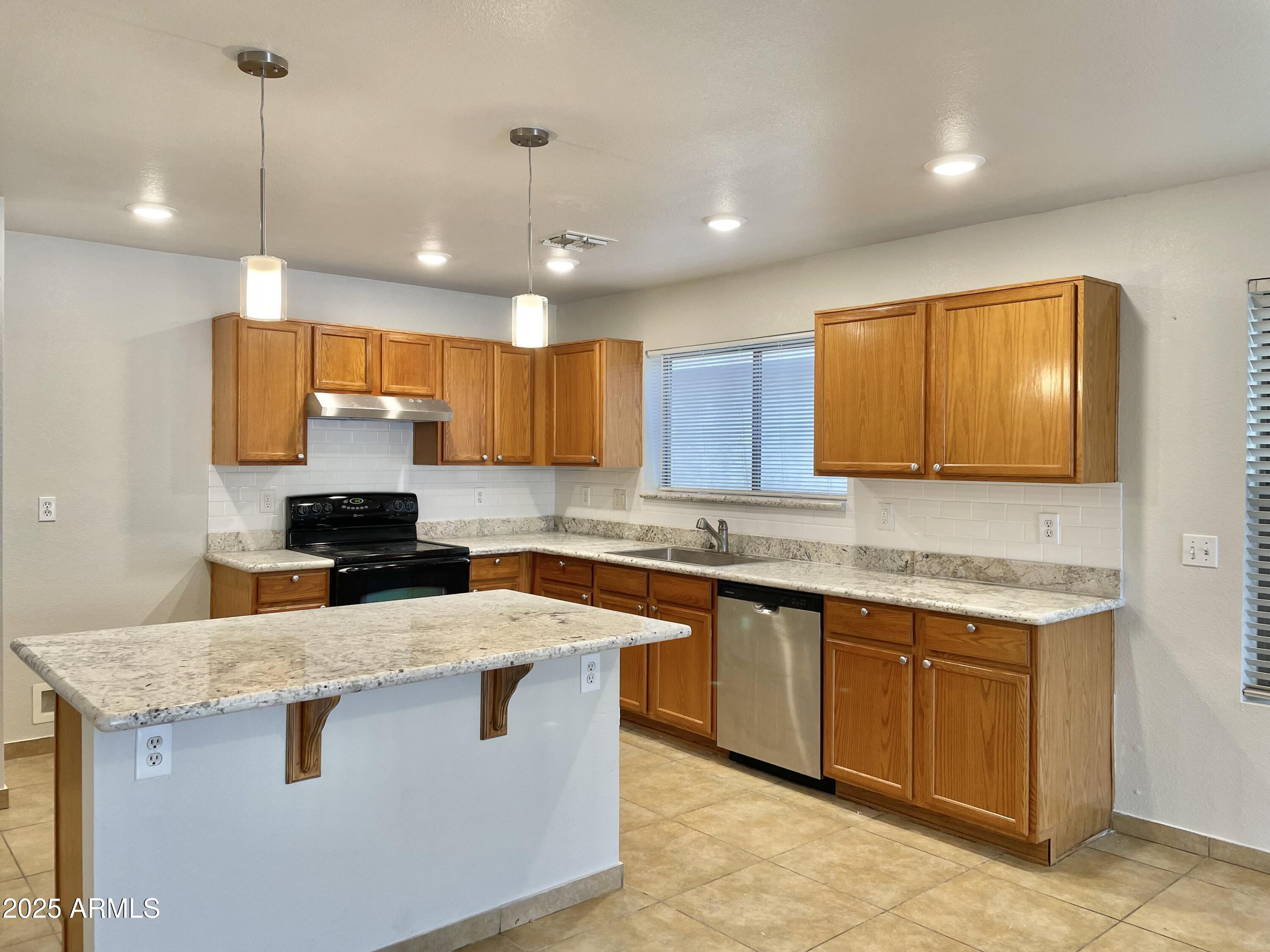 1002 East Arabian Drive Gilbert, AZ 85296 - Photo 8 of 23 a kitchen with kitchen island granite countertop wooden cabinets and a sink