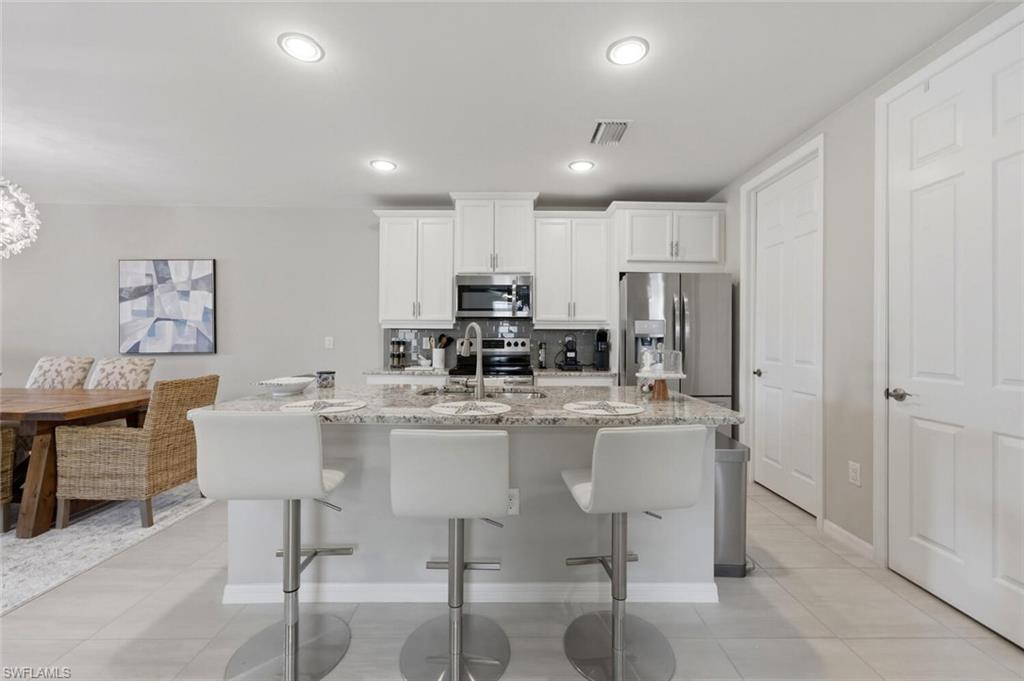 14827 Edgewater Circle Naples, FL 34114 - Photo 14 of 49 a kitchen with stainless steel appliances kitchen island granite countertop a table and chairs