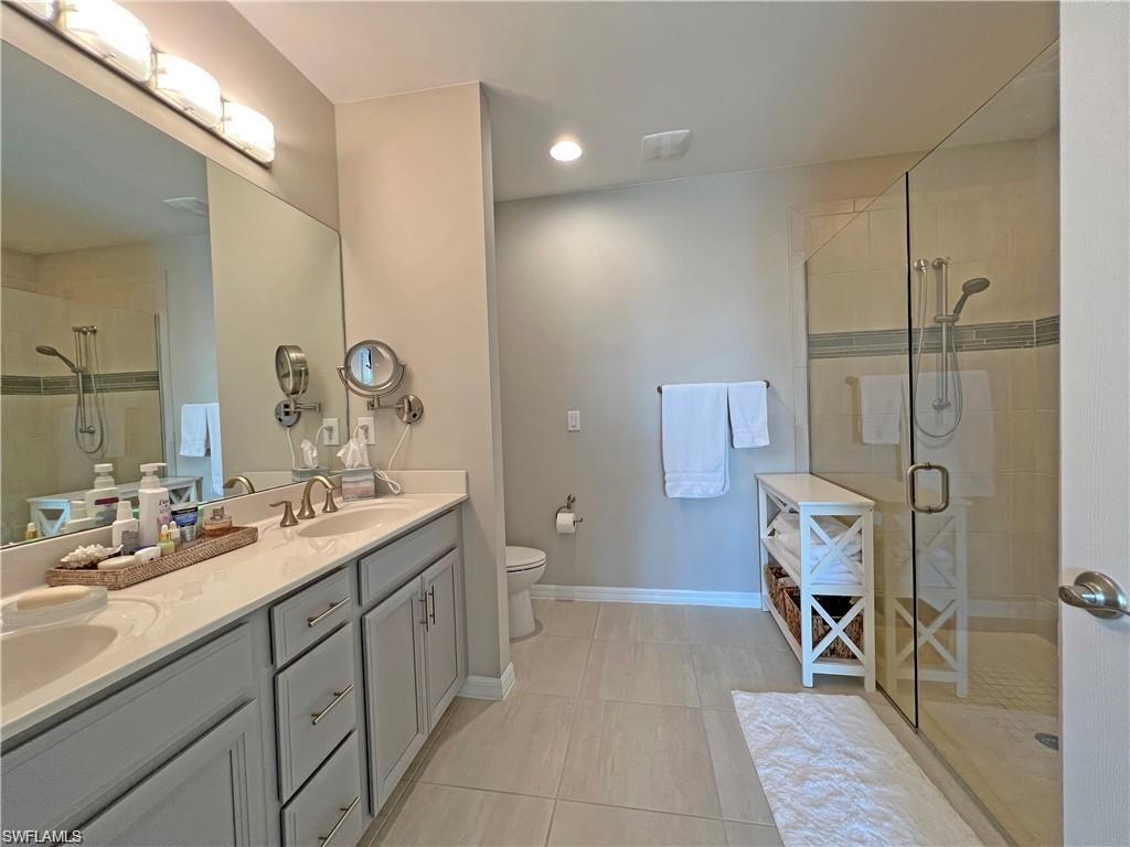 14827 Edgewater Circle Naples, FL 34114 - Photo 14 of 32 a en suite bathroom with a double vanity sink a mirror and a shower