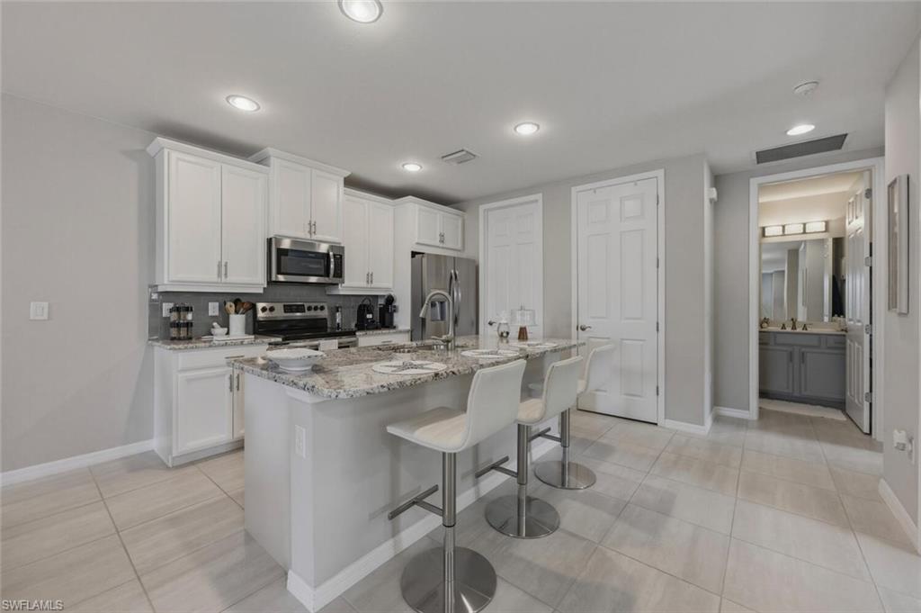 14827 Edgewater Circle Naples, FL 34114 - Photo 15 of 49 a kitchen with kitchen island granite countertop a sink a counter top space appliances and cabinets