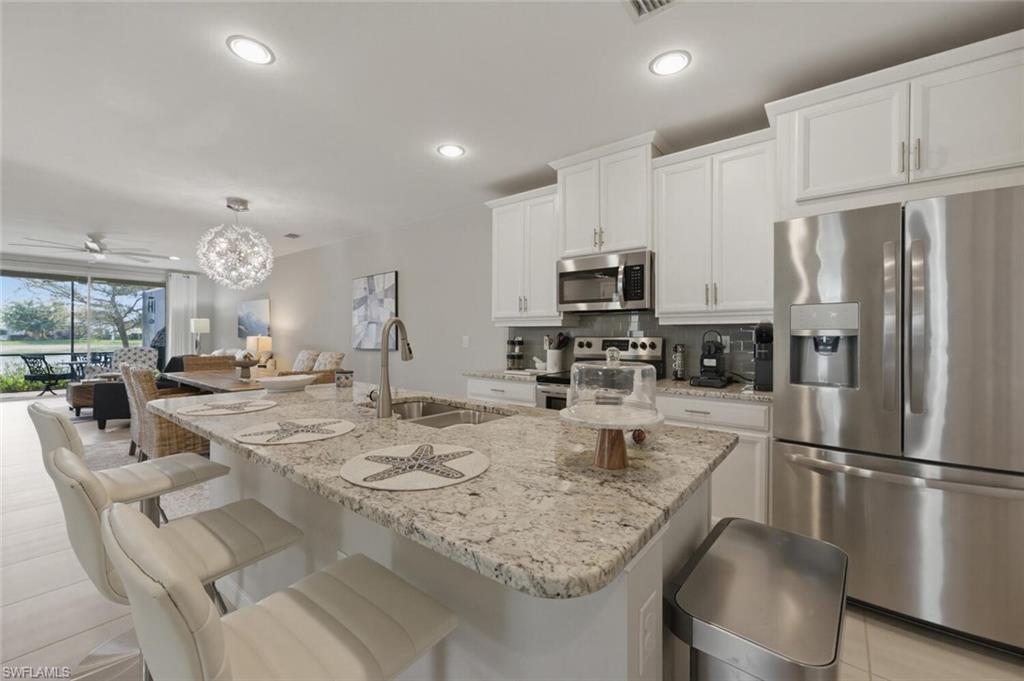 14827 Edgewater Circle Naples, FL 34114 - Photo 17 of 49 a kitchen with stainless steel appliances granite countertop a sink refrigerator and microwave
