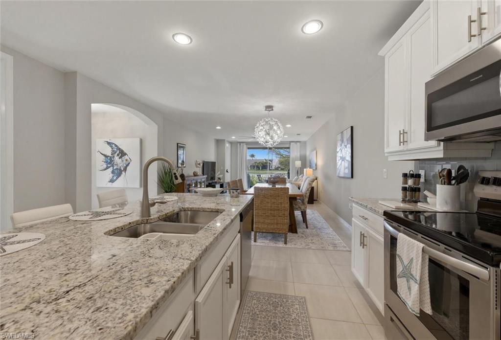 14827 Edgewater Circle Naples, FL 34114 - Photo 18 of 49 a kitchen with sink a stove and cabinets