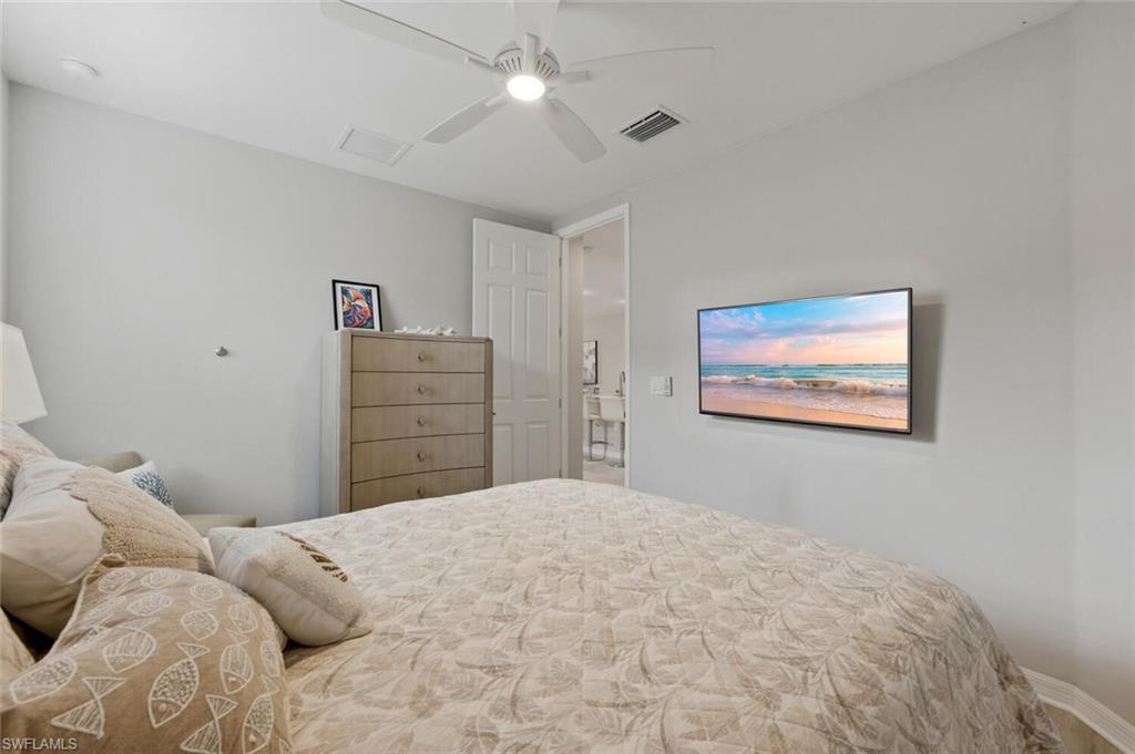 14827 Edgewater Circle Naples, FL 34114 - Photo 26 of 49 a bedroom with a bed and a chandelier