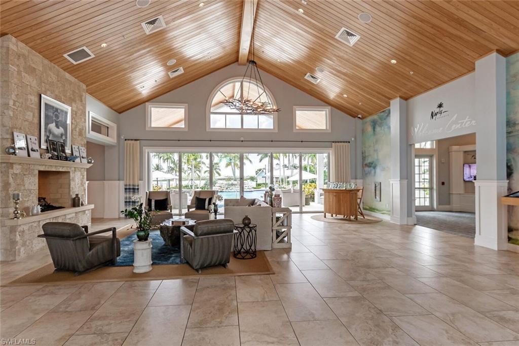 14827 Edgewater Circle Naples, FL 34114 - Photo 40 of 49 a living room with furniture a large window a rug and chandelier