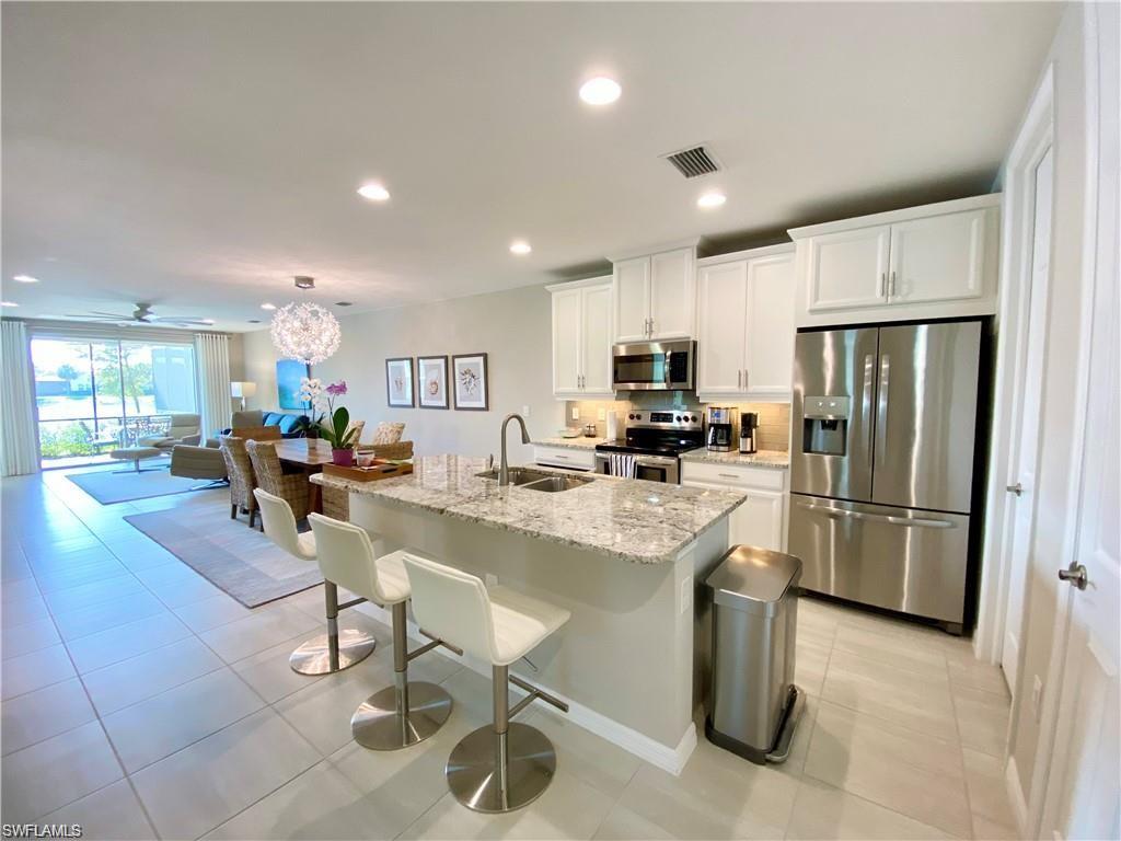 14827 Edgewater Circle Naples, FL 34114 - Photo 7 of 32 a kitchen with refrigerator and chairs