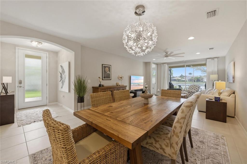14827 Edgewater Circle Naples, FL 34114 - Photo 10 of 49 a dining room with furniture a chandelier and wooden floor