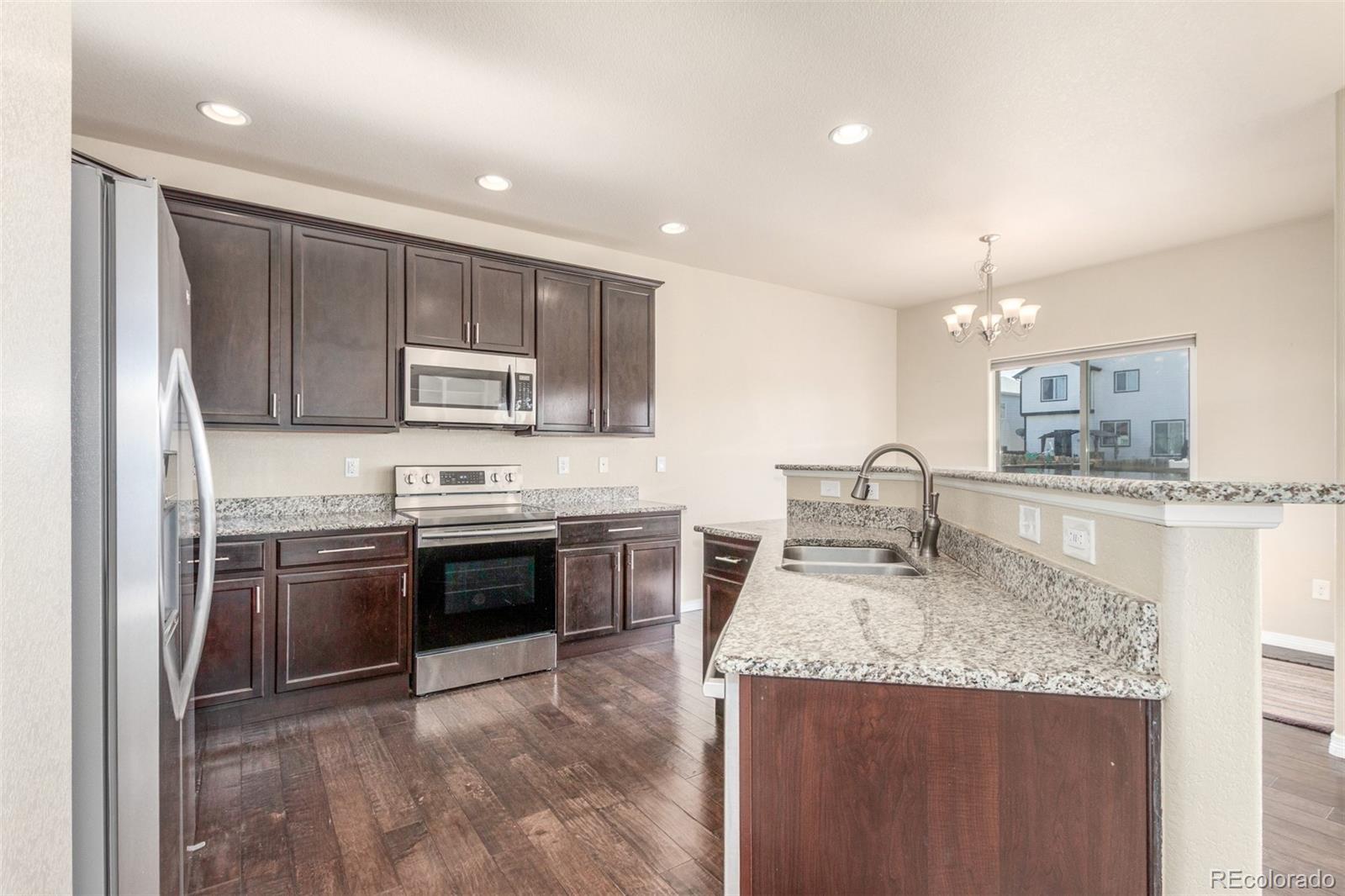 6654 12th Street Frederick, CO 80530 - Photo 13 of 50 a kitchen with stainless steel appliances granite countertop a sink stove and refrigerator