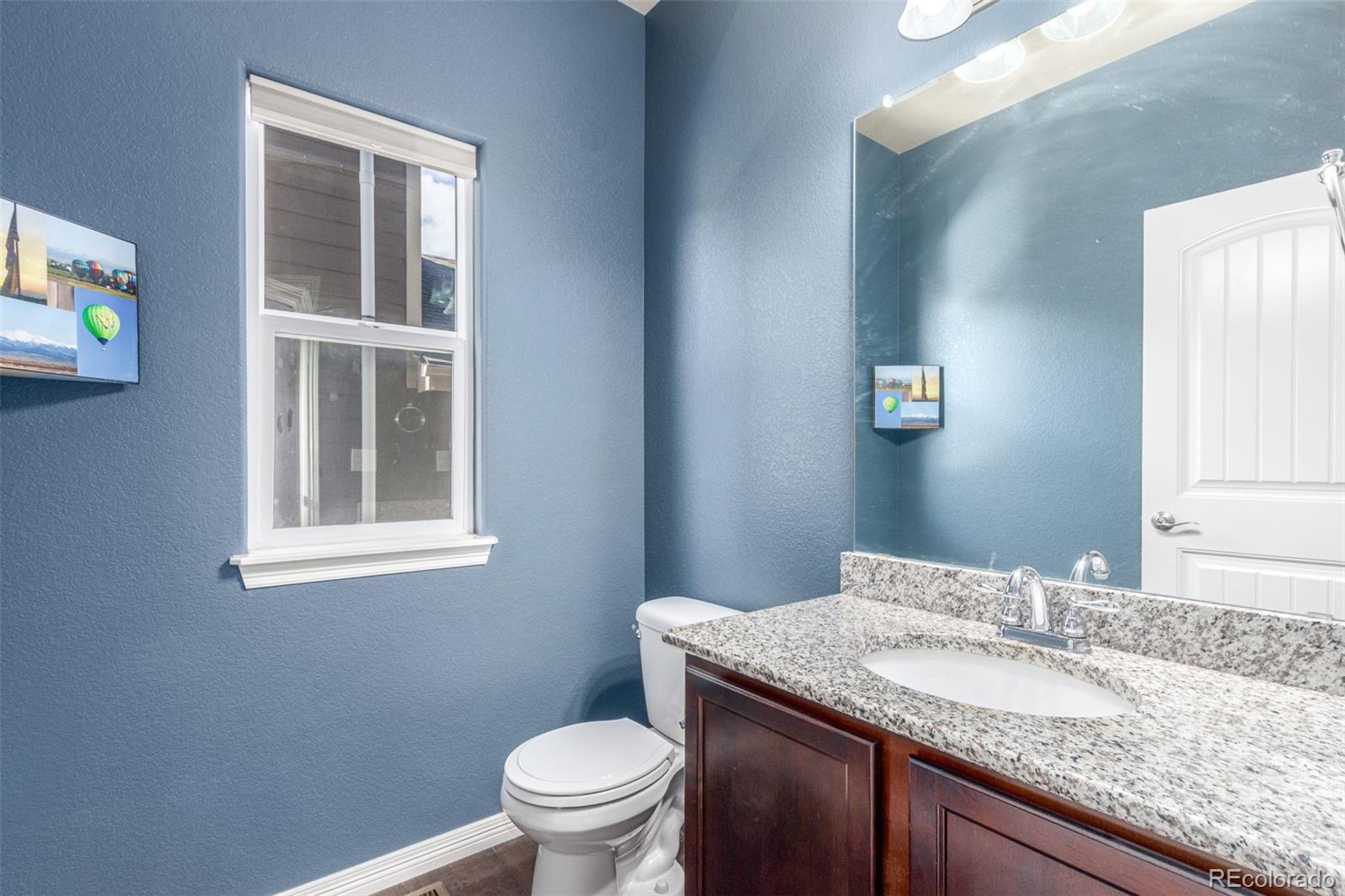 6654 12th Street Frederick, CO 80530 - Photo 17 of 50 a bathroom with a granite countertop sink a mirror and a toilet
