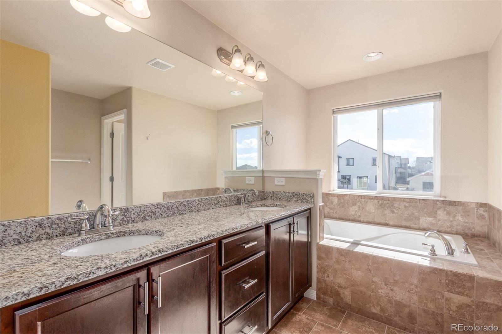 6654 12th Street Frederick, CO 80530 - Photo 20 of 50 a bathroom with a granite countertop sink a large mirror and a bathtub