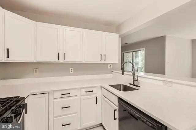 a kitchen with white cabinets and sink