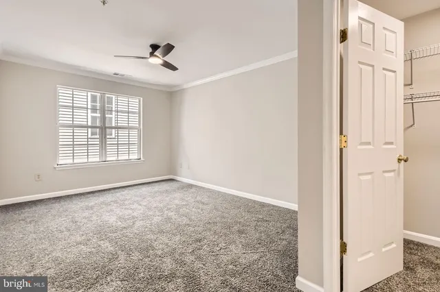 an empty room with a ceiling fan and a window