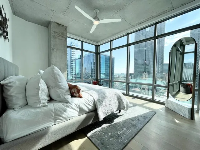 a large bedroom with bed and glass windows