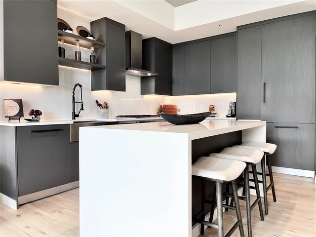 a kitchen with stainless steel appliances kitchen island granite countertop a table chairs and a refrigerator