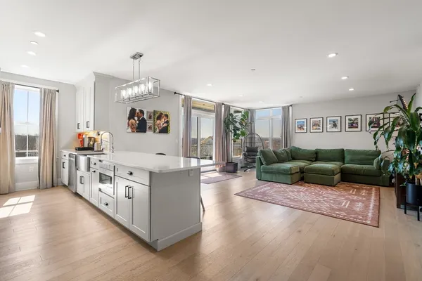 a large white kitchen with stainless steel appliances granite countertop a lot of counter space and a wooden floor