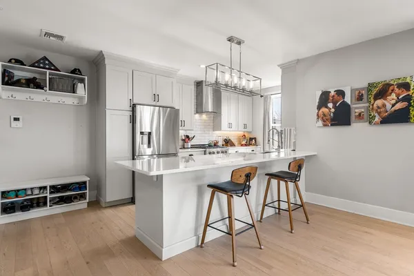 a kitchen with stainless steel appliances a dining table chairs refrigerator and stove top oven