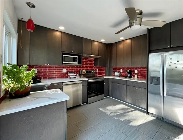 a kitchen with stainless steel appliances kitchen island granite countertop a refrigerator and a stove top oven