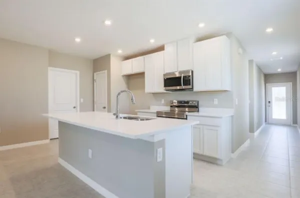 a view of large kitchen with stainless steel appliances kitchen island a sink wooden floor and a living room view
