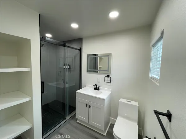 a bathroom with a toilet a sink a glass door a shower a mirror and a sink