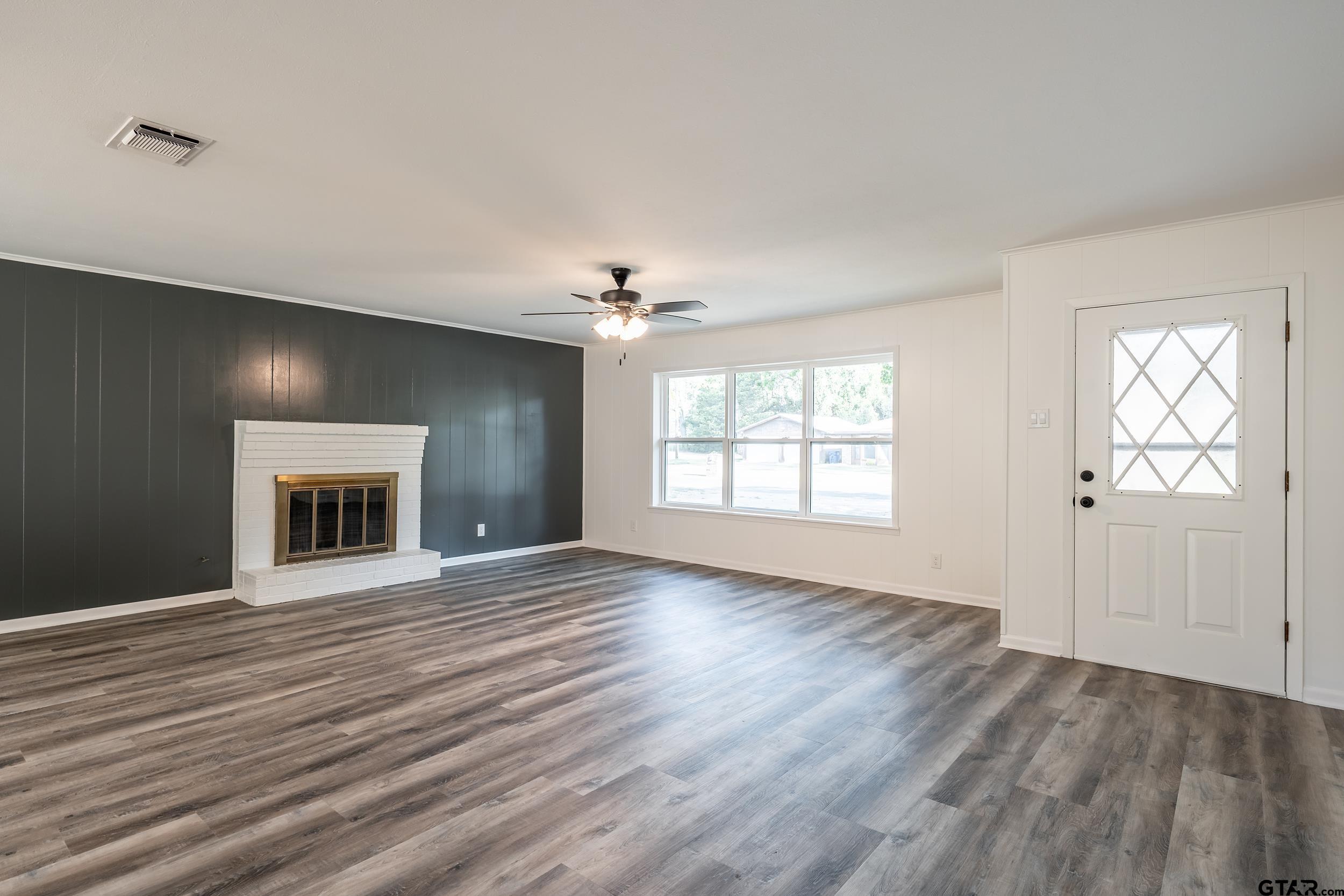 2201 King Road Jacksonville, TX 75766 - Photo 4 of 24 an empty room with wooden floor and windows