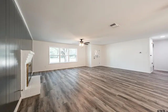 an empty room with wooden floor cabinet and windows