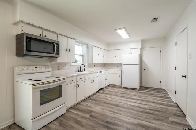 a view of a kitchen with sink microwave and cabinets