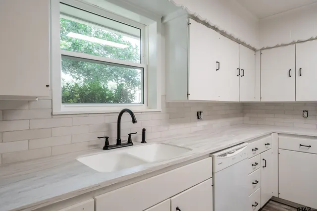 a kitchen with white cabinets a sink and a window