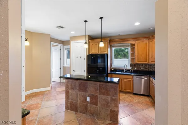 a kitchen with kitchen island granite countertop a stove a sink a counter top space and cabinets