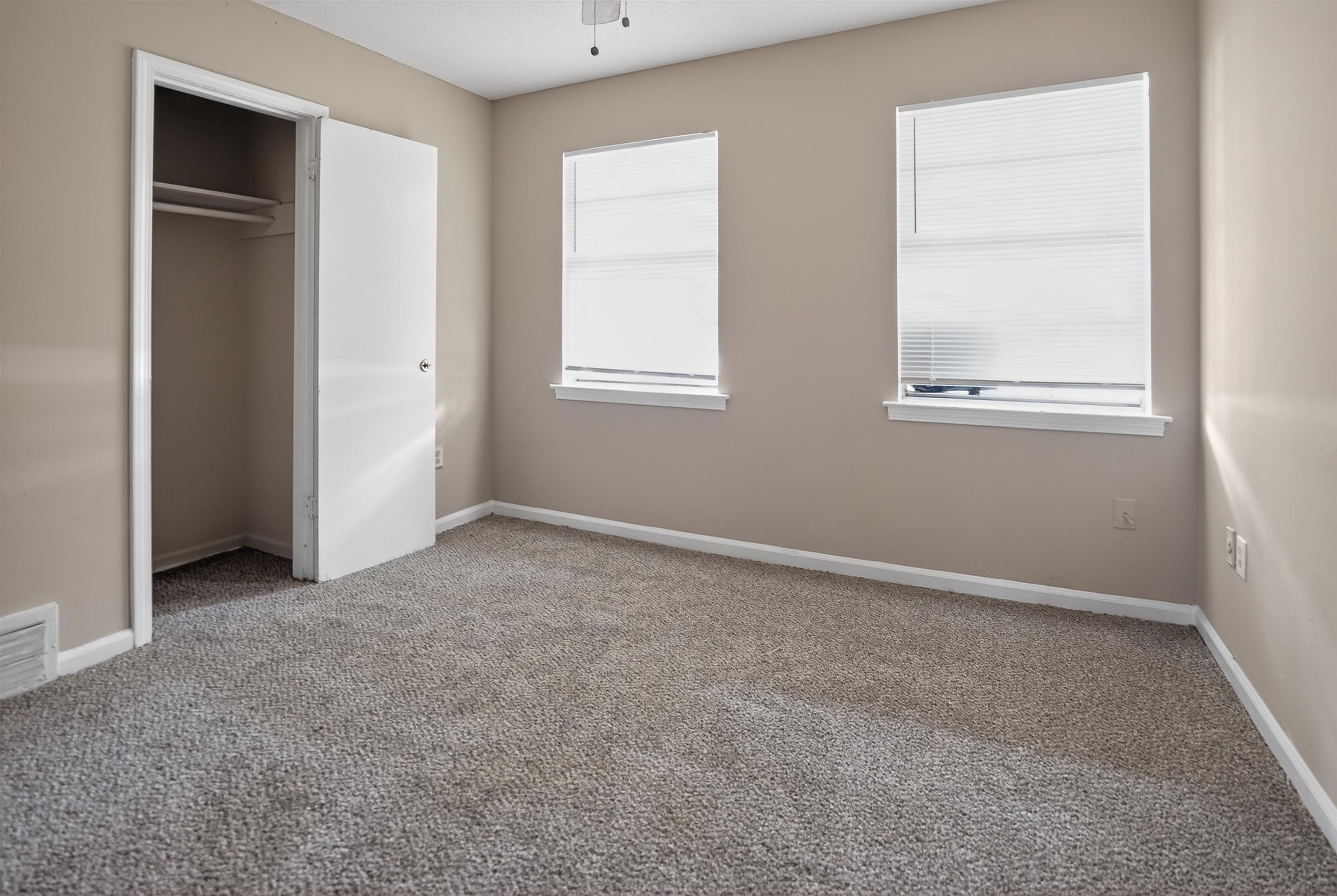 4530 Spring Valley Drive Memphis, TN 38128 - Photo 12 of 15 Carpeted room featuring two windows with blinds, a white trim package, and a closet with a bi-fold door
