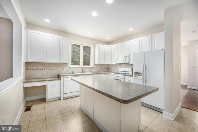 a kitchen with a sink a stove a refrigerator and white cabinets