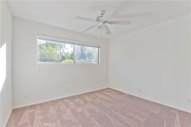 an empty room with a window and a fan