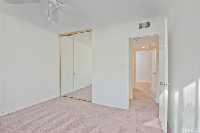 an empty room with a fan & a mirror