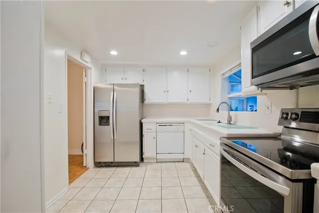 a kitchen with a refrigerator sink and cabinets