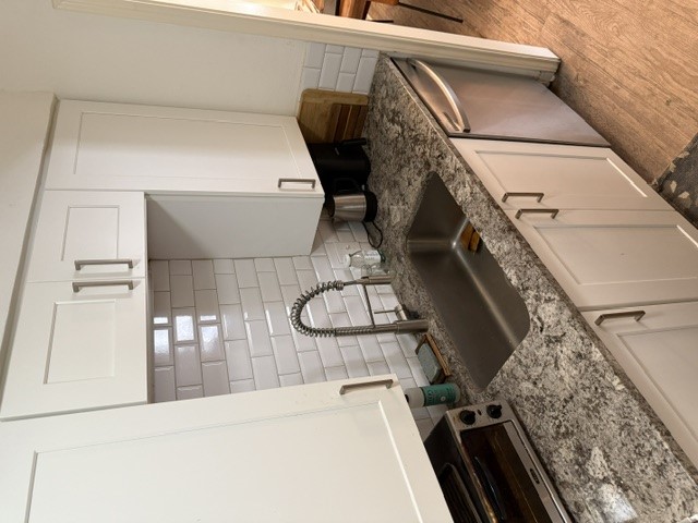 a kitchen with granite countertop a sink and a stove