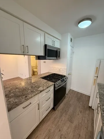 a kitchen with granite countertop a sink and a stove top oven