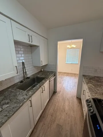 a kitchen with granite countertop a sink stove and cabinets